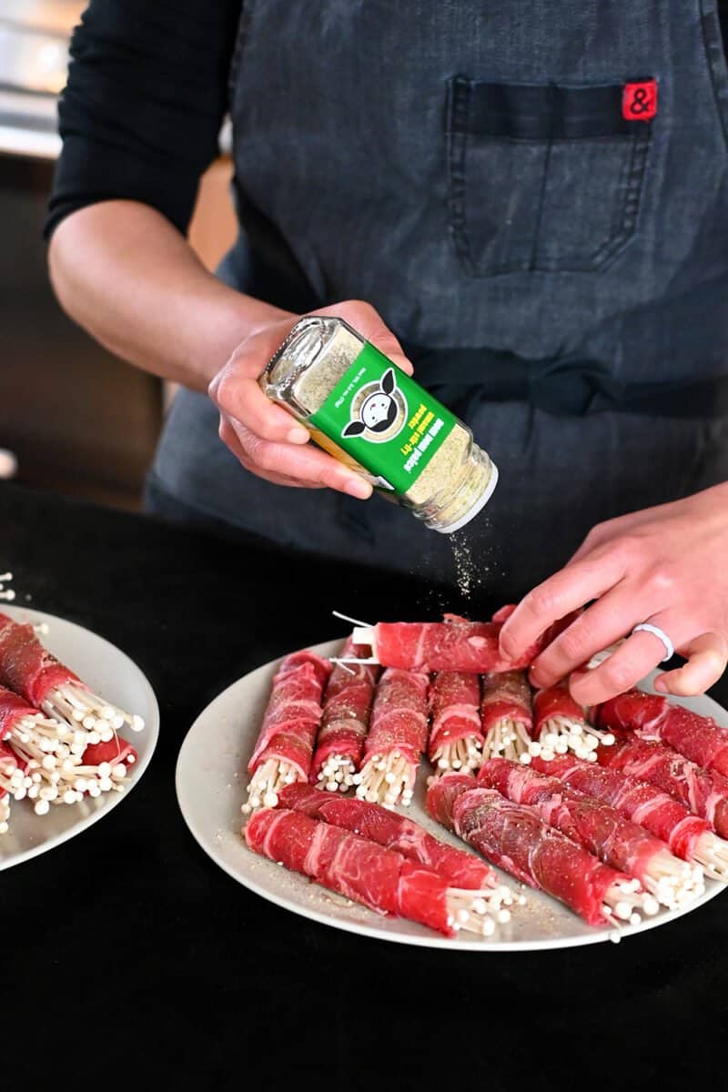 Sprinkling Umami Stir-Fry Powder on some beef and enoki rolls.
