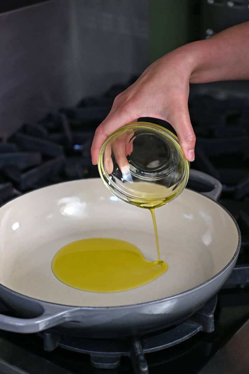 Pouring olive oil in a large skillet in preparation of making Veracruz sauce.