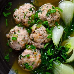 An overhead shot of a bowl with wonton meatballs and baby Bok Choy in a bowl of clear broth.