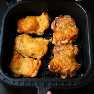 An overhead shot of crispy air fryer chicken thighs in an open air fryer basket.