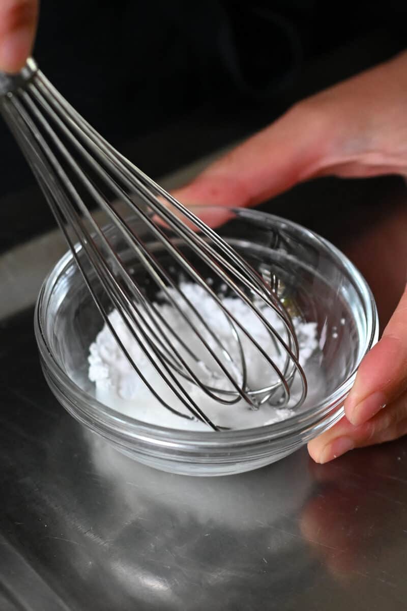 A closeup of arrowroot power and water whisked in a small bowl.