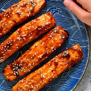 A blue plate with four air fryer salmon filets with honey sriracha glaze.