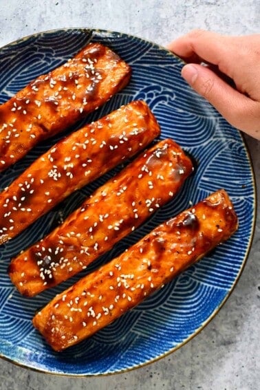 A blue plate with four air fryer salmon filets with honey sriracha glaze.