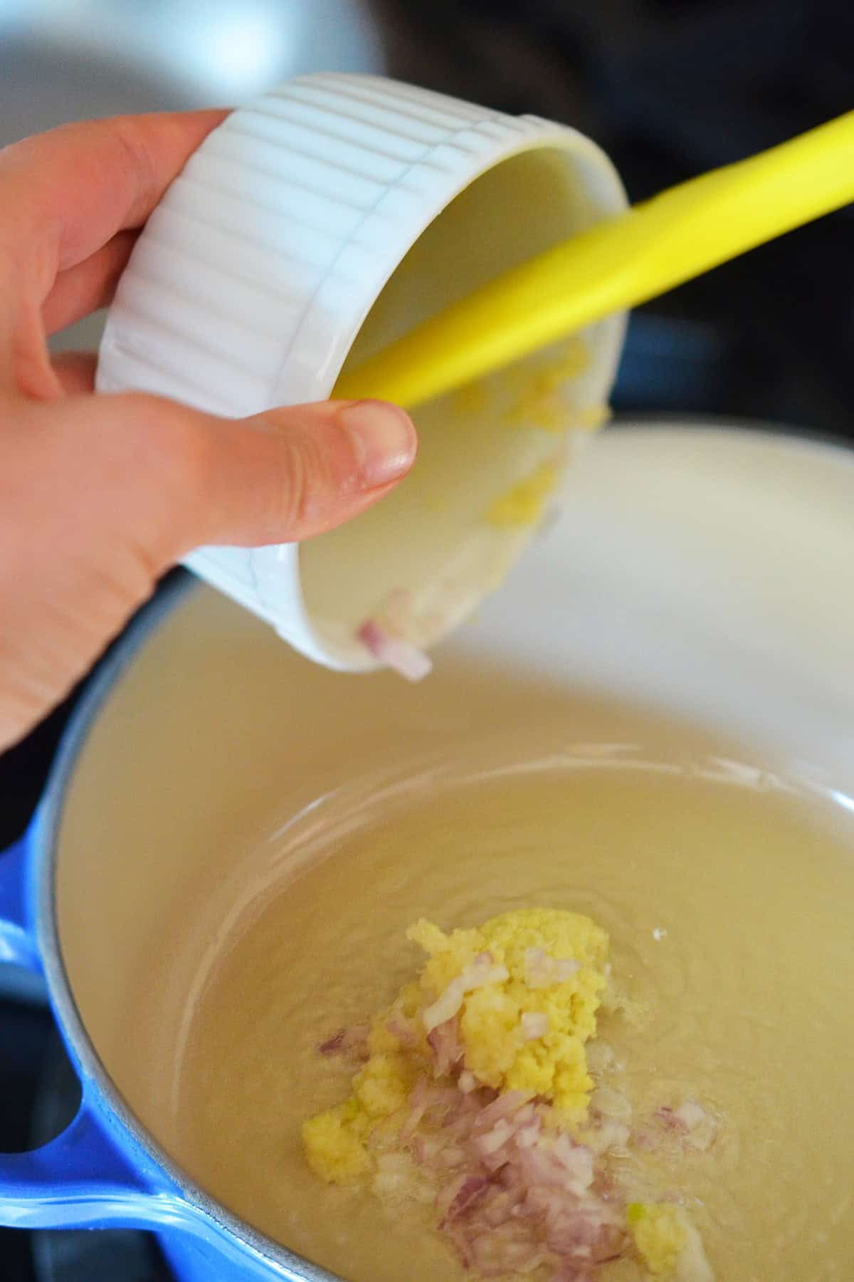 Sautéing minced shallot, garlic, and ginger in some fat in a small saucepan.