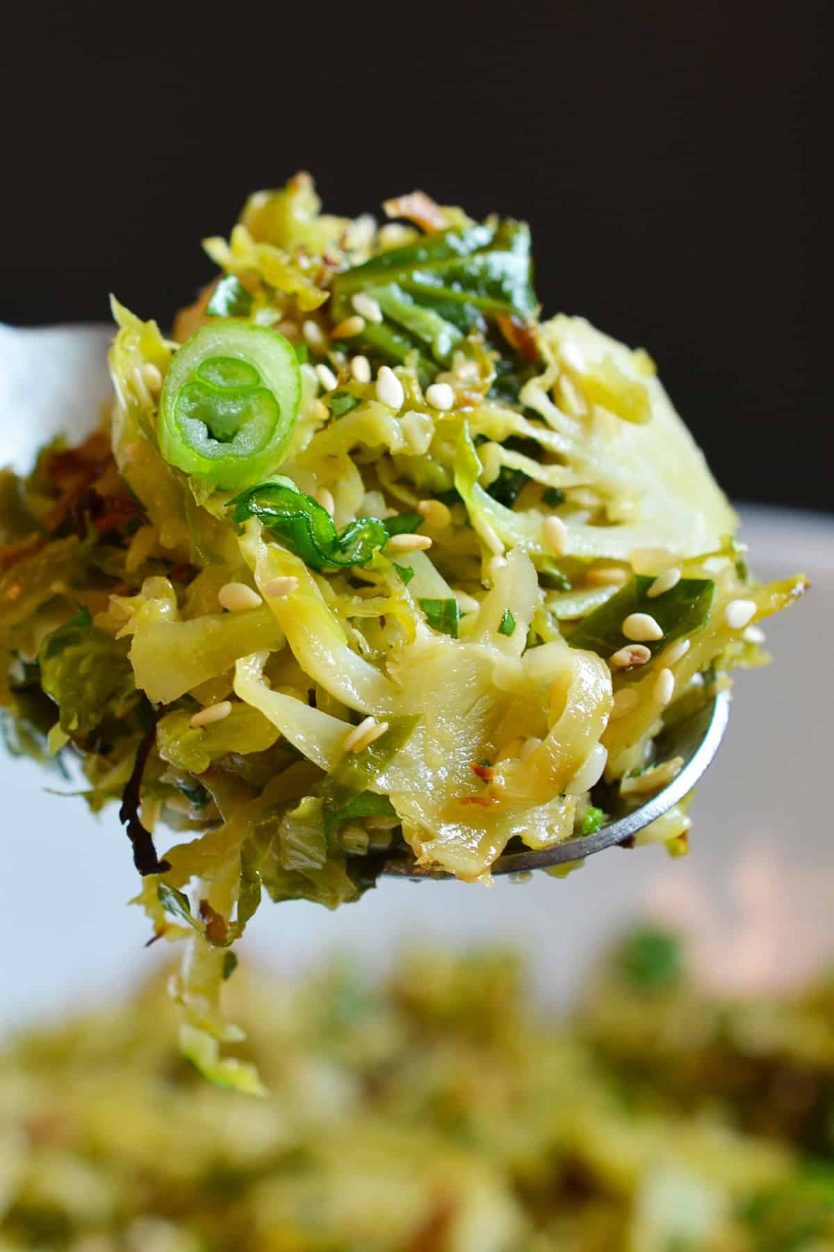 A closeup of a spoonful of roasted Brussels sprouts salad with Asian citrus dressing.