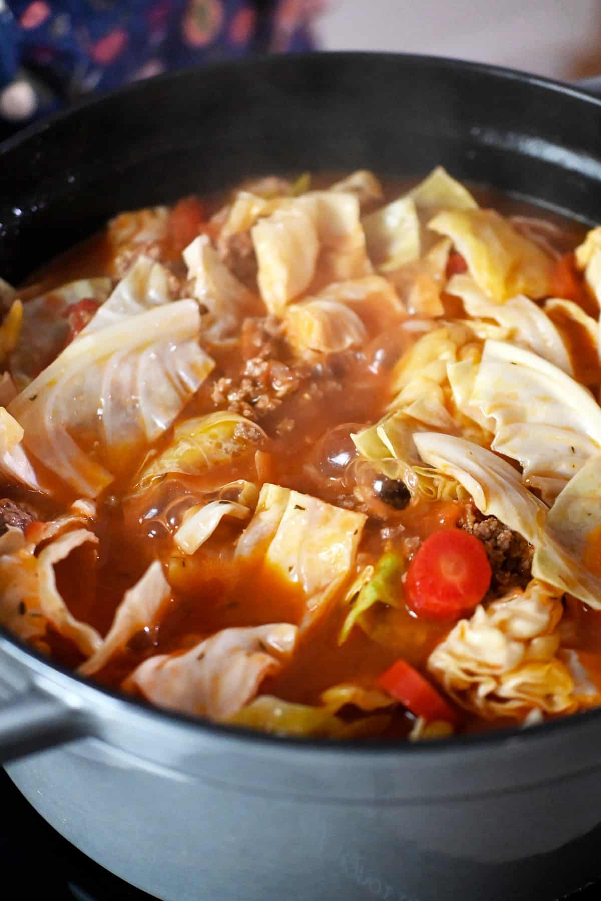 A close-up of a pot of cabbage roll soup simmering on a stove top.