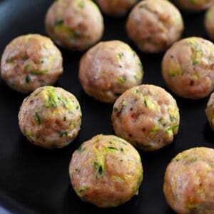 A black plate topped with paleo baked chicken meatballs made with shredded zucchini.