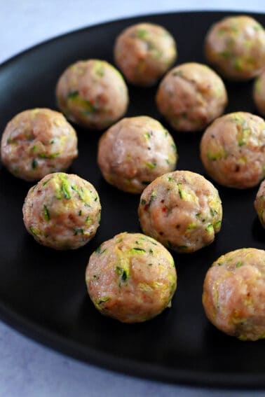 A black plate topped with paleo baked chicken meatballs made with shredded zucchini.