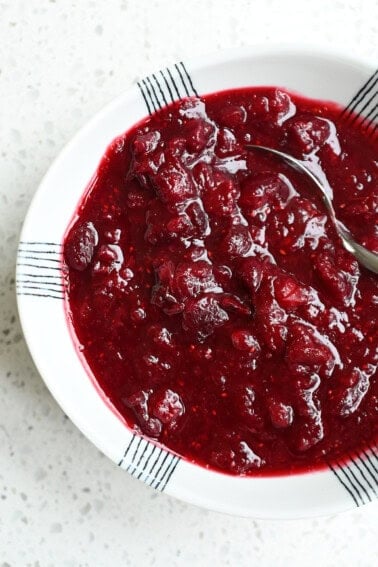 An overhead shot of a white bowl filled with homemade paleo cranberry sauce with cherries.
