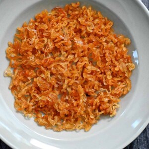An overhead shot of a light blue plate filled with golden brown crispy shallots.