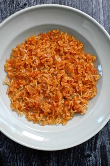 An overhead shot of a light blue plate filled with golden brown crispy shallots.