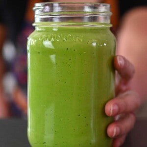 A hand is holding a mason jar filled with paleo, vegan, and Whole30 Green Goddess Dressing.
