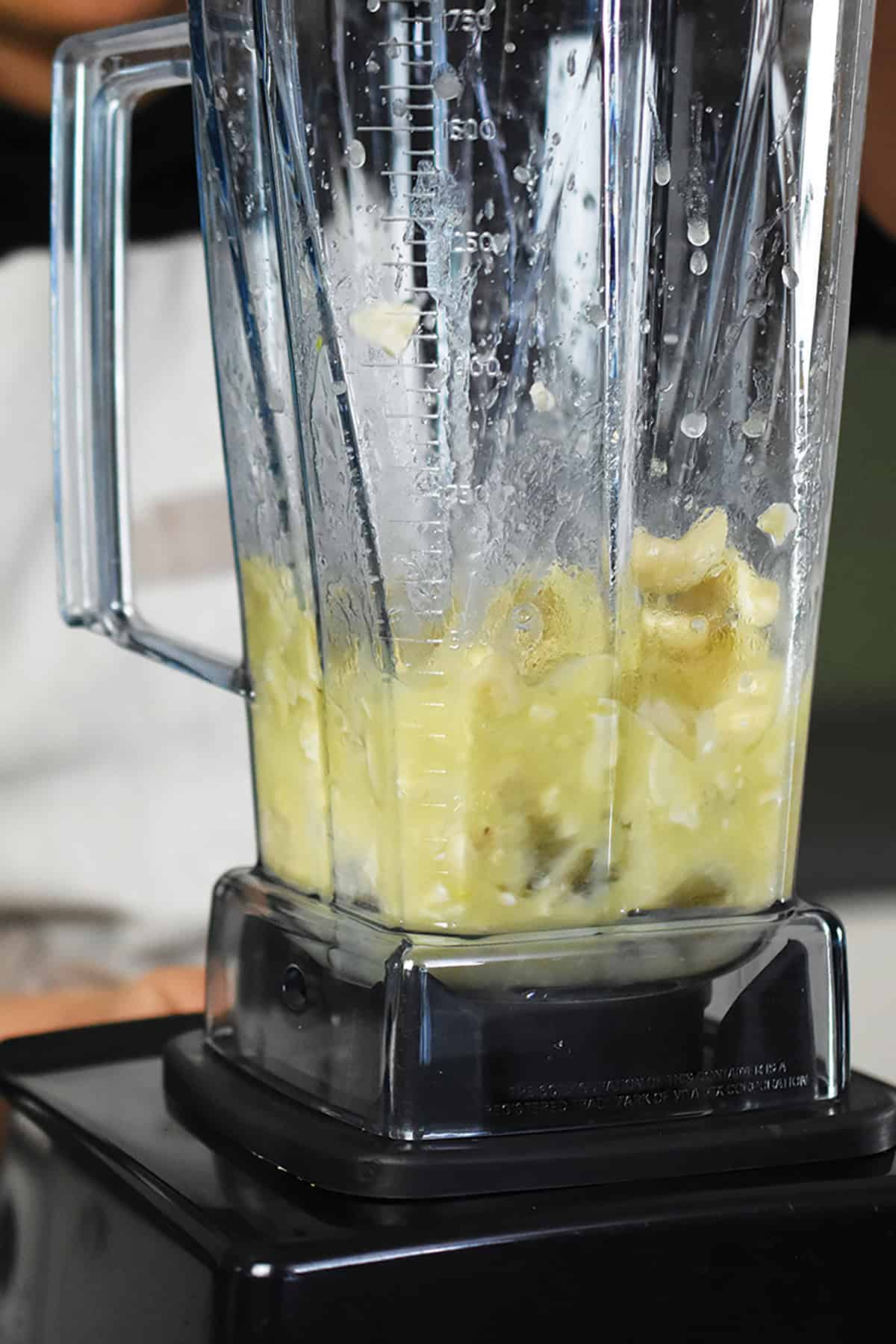 A Vitamix blender is blending up a cashew cream.