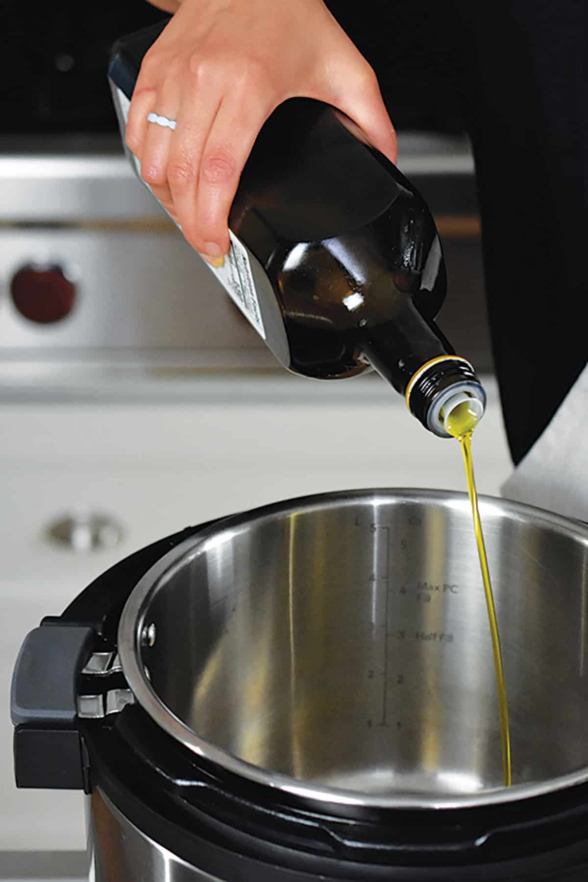 Pouring extra virgin olive oil into an open Instant Pot.
