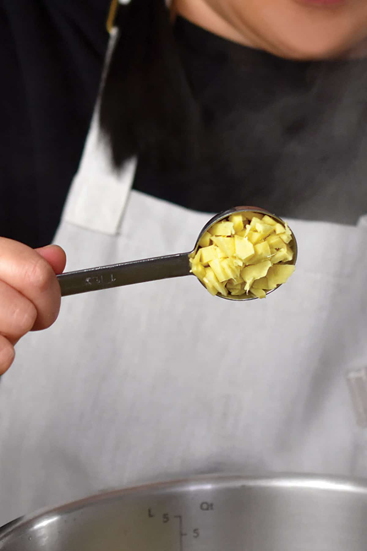 Adding a spoonful of chopped ginger to an Instant Pot to make green soup.