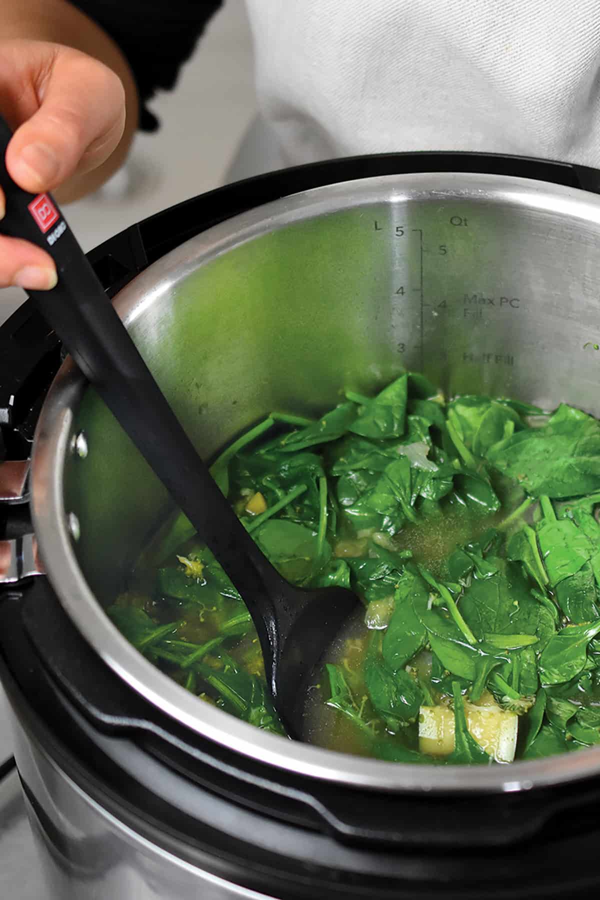 An overhead shot of an open Instant Pot filled with the ingredients of cooked green soup, ready to be blended.