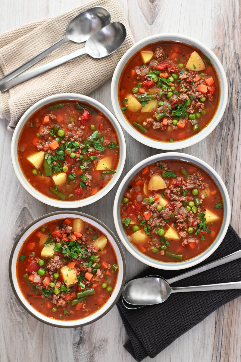 An overhead shot of four bowls of hamburger soup.
