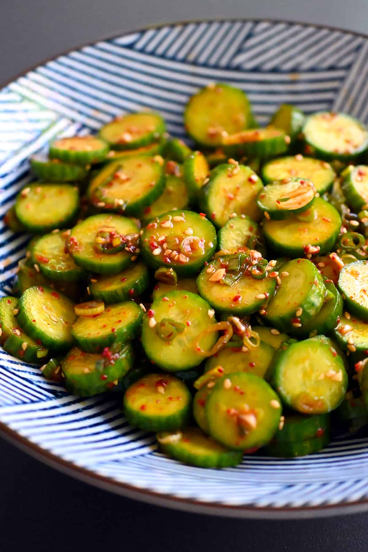 An closeup shot of a blue and white serving bowl with paleo and gluten free Korean cucumber salad.