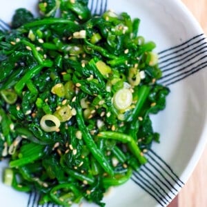 An overhead shot of a white and blue serving bowl filled with Korean spinach side dish.
