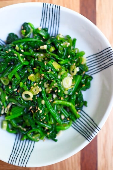 An overhead shot of a white and blue serving bowl filled with Korean spinach side dish.