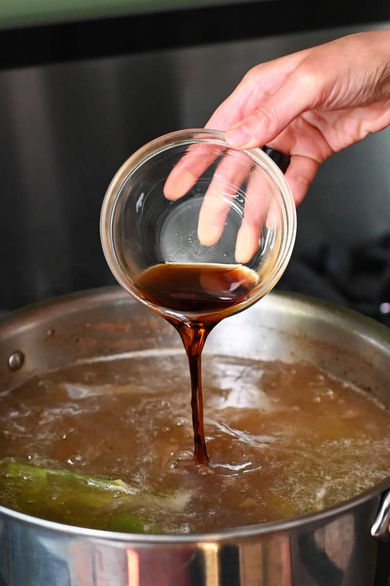 Pouring a bowl of fish sauce into a pot of oxtail soup