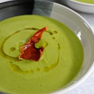 A closeup shot of pea soup with crispy prosciutto on top