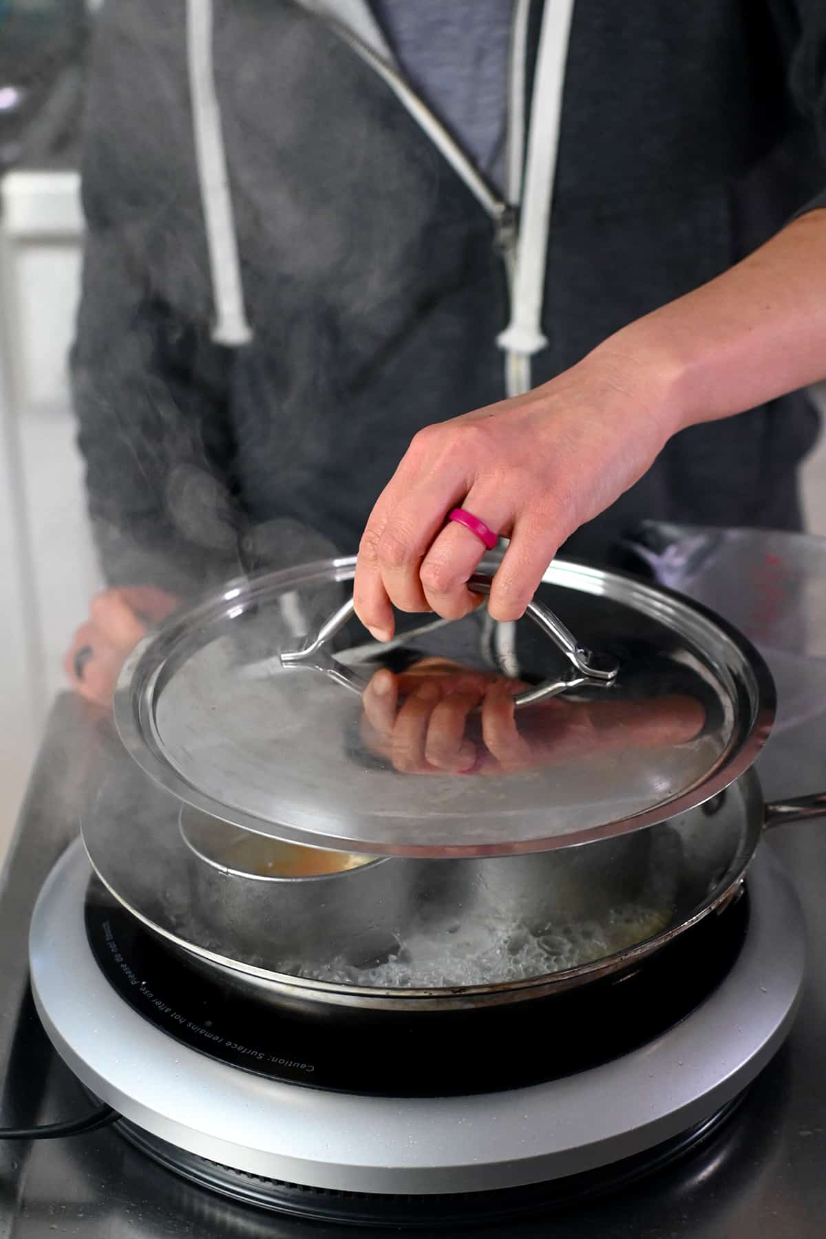 Putting a lid on a skillet filled with steaming water and eggs.
