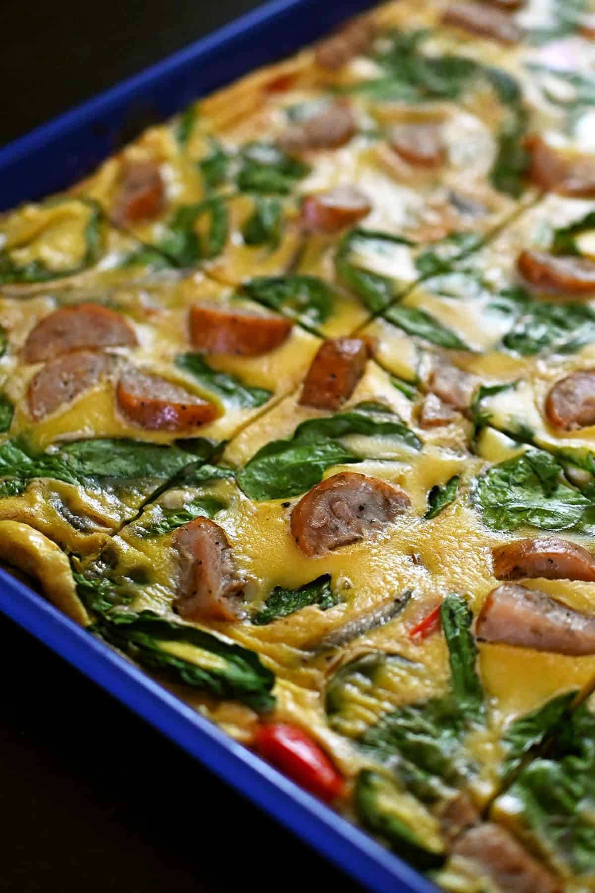 A side view of a blue sheet pan filled with sliced sheet pan eggs.