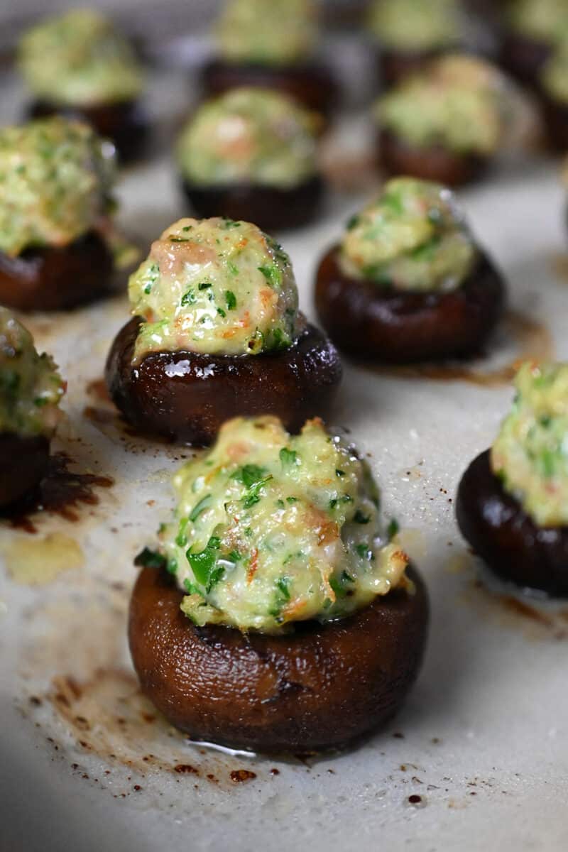 A closeup of freshly baked Chinese-inspired shrimp stuffed mushrooms on a parchment lined baking tray.