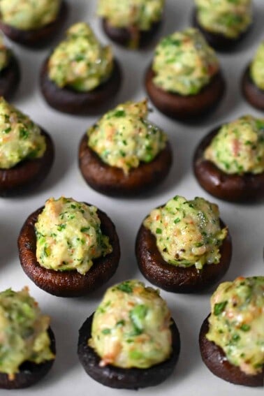 A closeup of freshly baked Chinese-inspired shrimp stuffed mushrooms on a parchment lined baking tray.