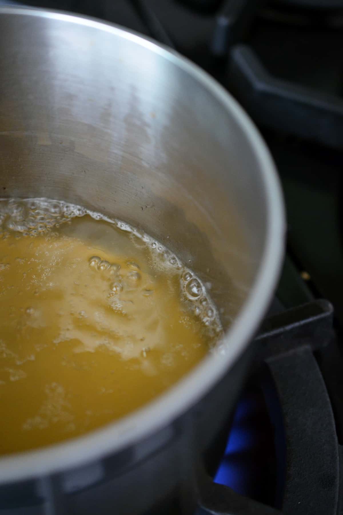 Boiling broth in a small saucepan over a gas stovetop.