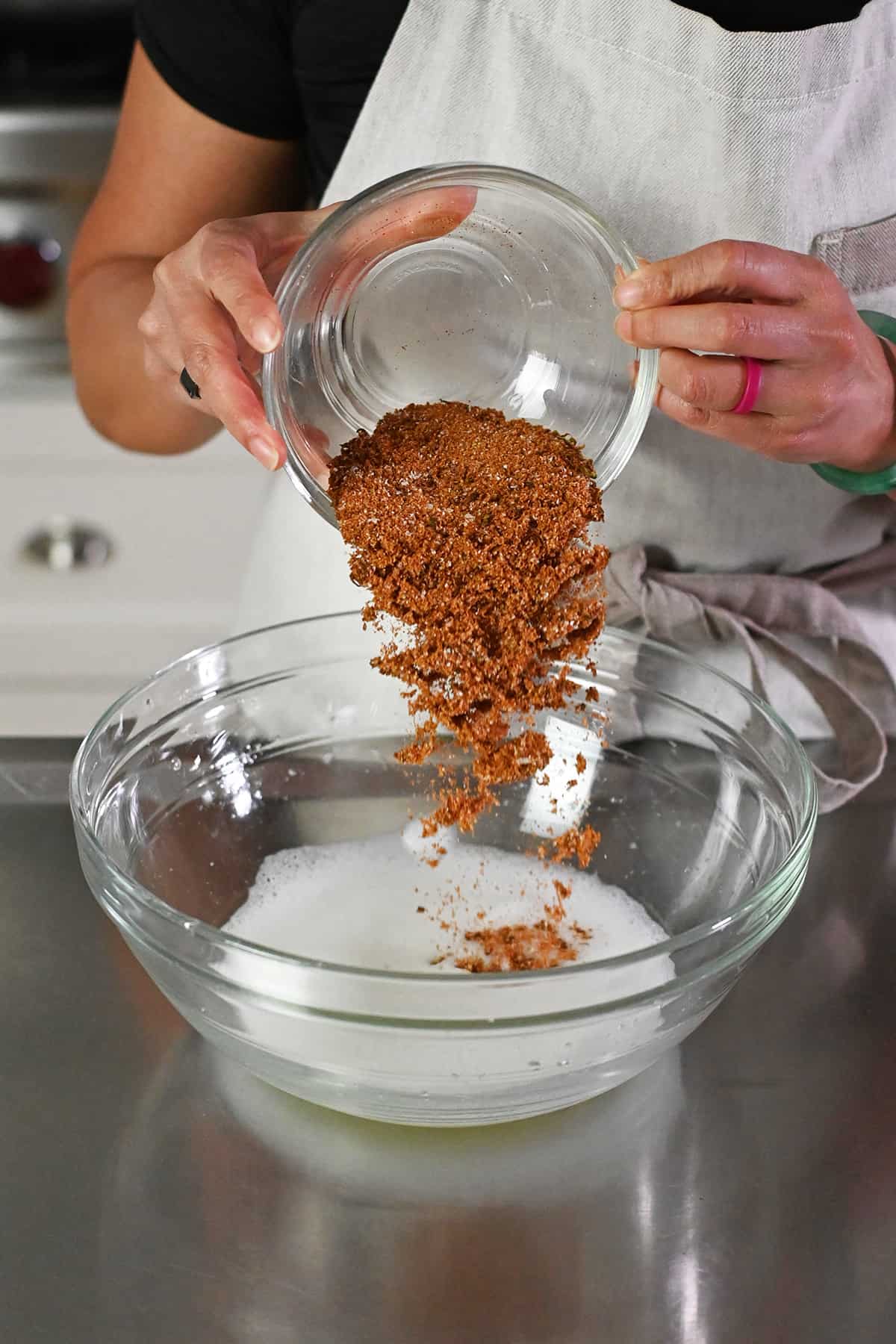 Pouring the spice blend into a large bowl filled with frothy whipped egg whites.