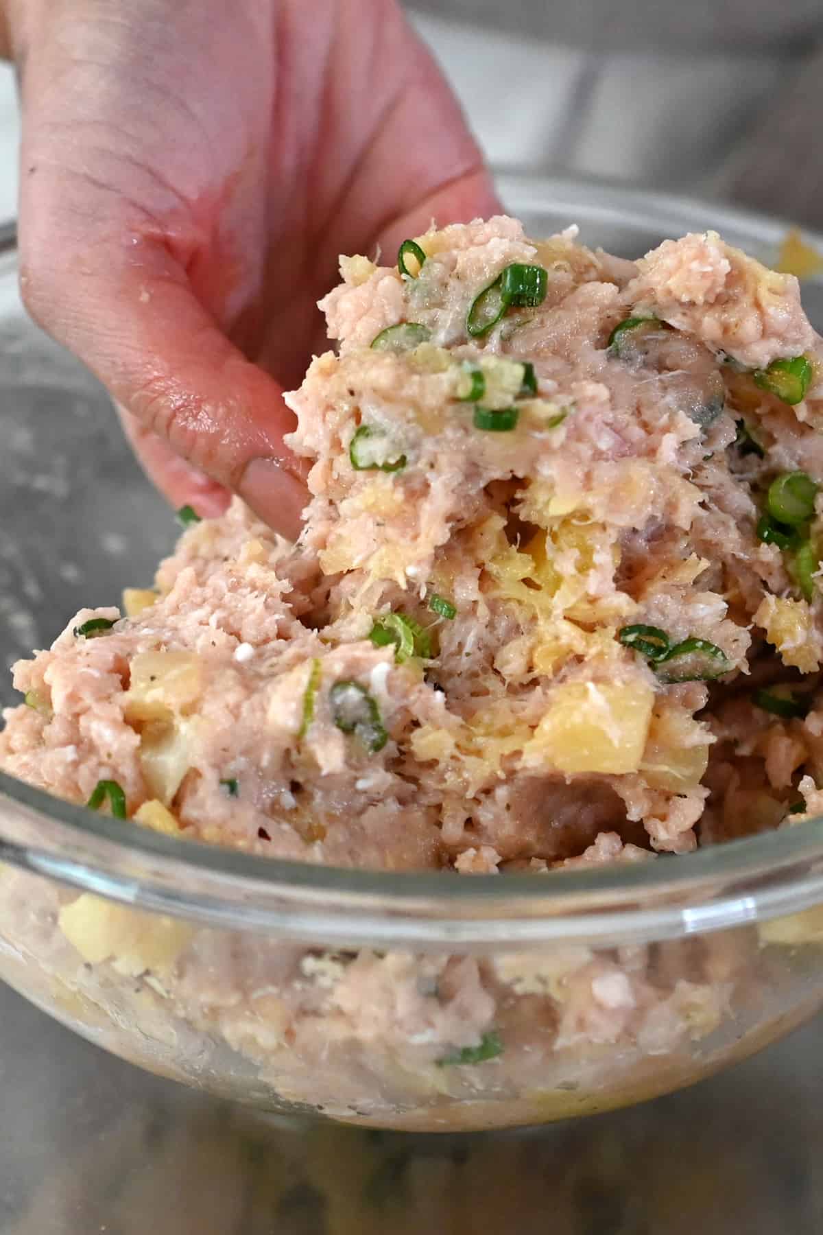 Mixing paleo teriyaki pineapple chicken meatball ingredients with clean hands.