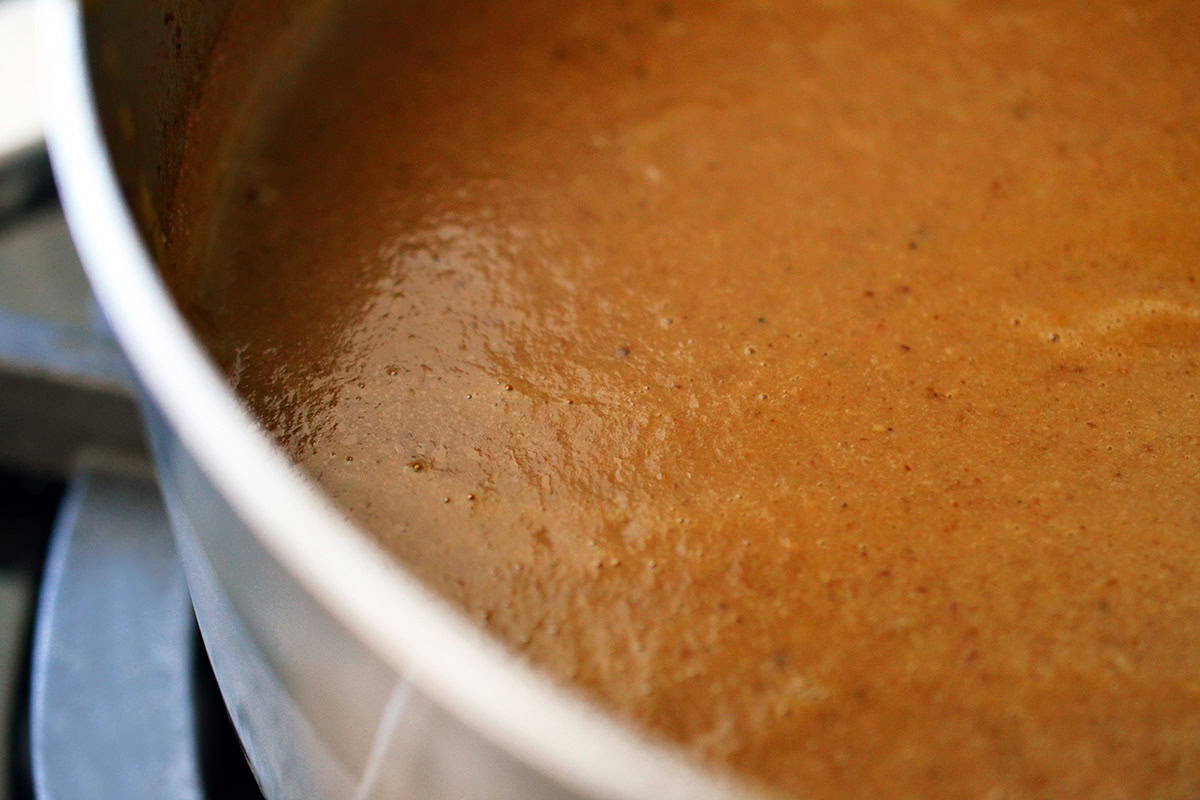 An overhead shot of a saucepan filled with a smooth gluten free gravy that is packed with umami flavor.