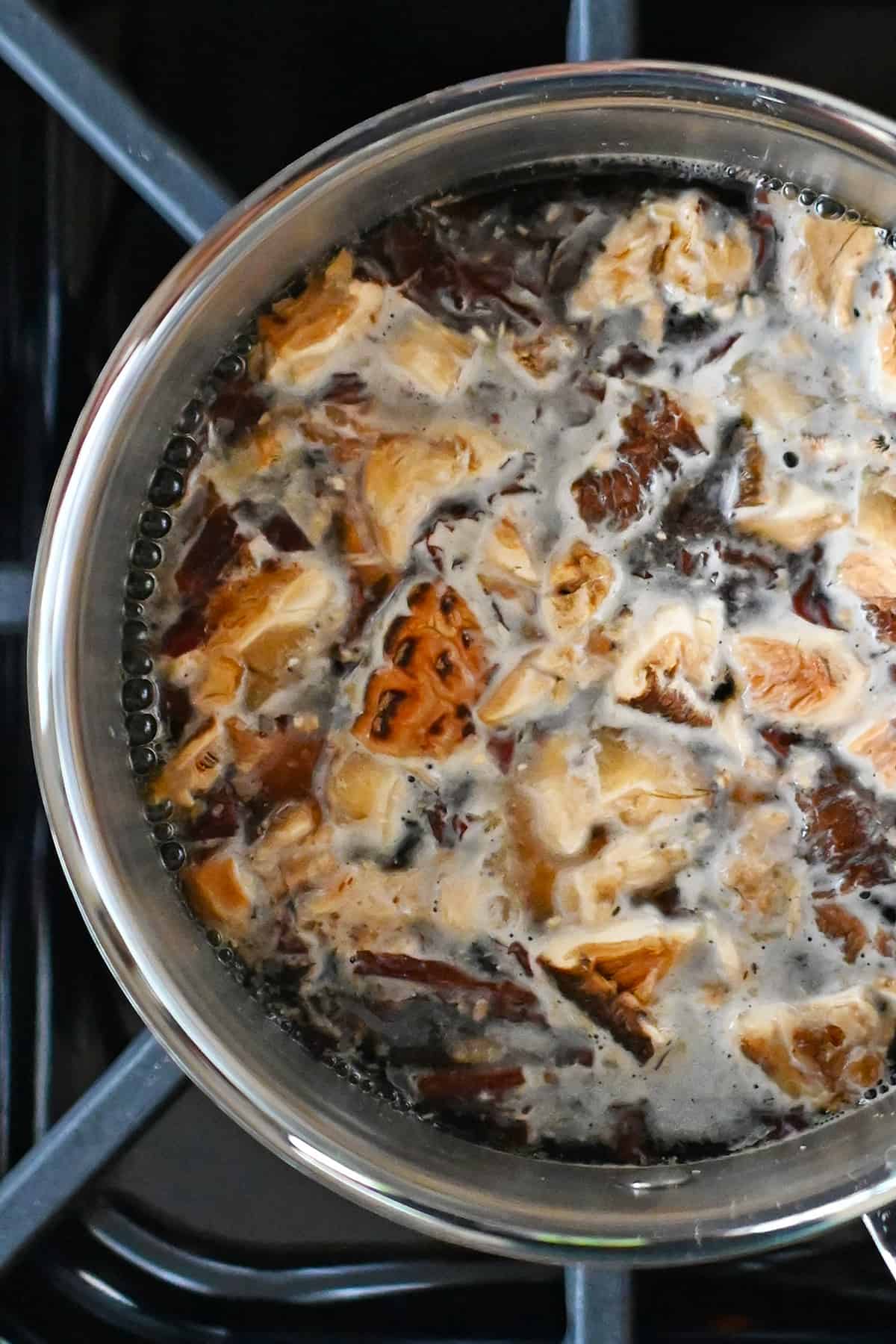 An overhead shot of a small saucepan filled with the simmering ingredients for homemade vegan fish sauce.