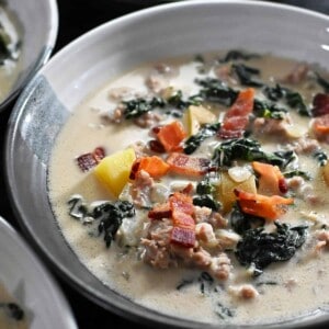 A closeup of a bowl of Whole30 Zuppa Toscana soup topped with crispy bacon bits.
