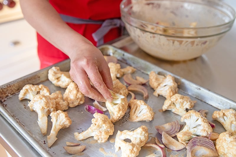 Arranging tandoori-marinated cauliflower and onions on a sheet pan.