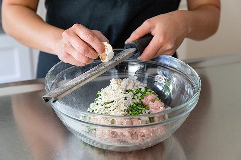 Grating a dried shiitake mushroom onto the paleo tsukune meatball mixture.