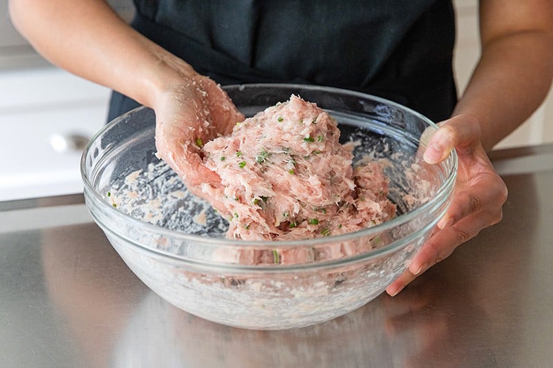 Kneading the paleo tsukune ground chicken mixture until it is sticky and tacky.