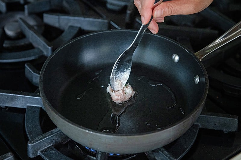 Frying a small patty of Japanese chicken meatball to taste for seasoning.