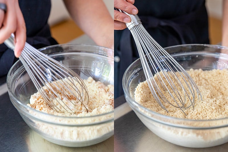 Whisking the dry ingredients for paleo pumpkin muffins in a clear large mixing bowl.