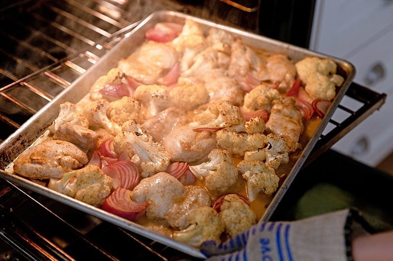 Rotating paleo sheet pan chicken tandoori at the halfway point in the oven. 