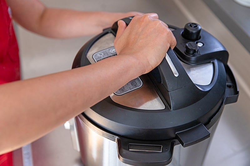 Someone locking the lid on an Instant Pot to make Instant Pot butternut squash soup.