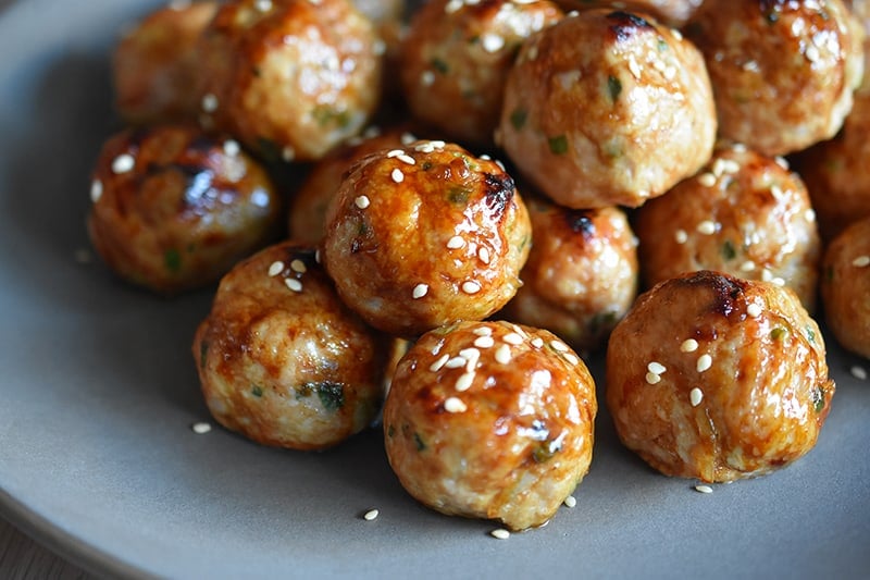 A side shot of a platter of paleo tsukune, gluten-free Japanese ground chicken meatballs.