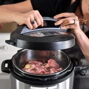 A person is placing the lid on top of the Instant Pot .