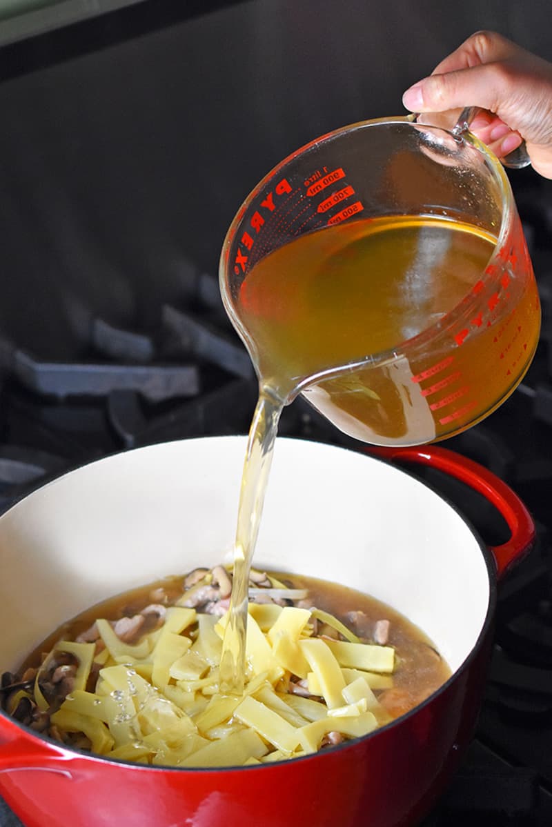 Pouring broth in the pot to make Hot and Sour Soup.