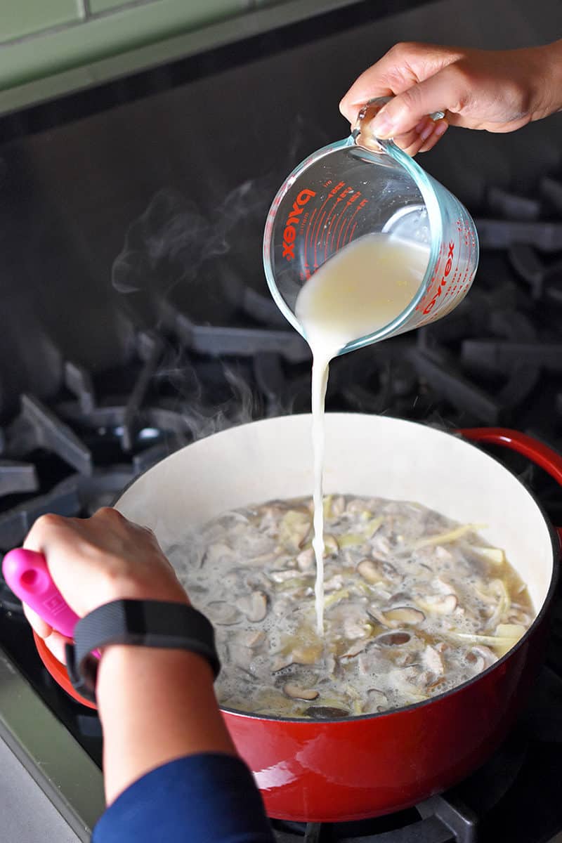 Pouring the arrowroot powder slurry into the simmering Hot and Sour Soup.