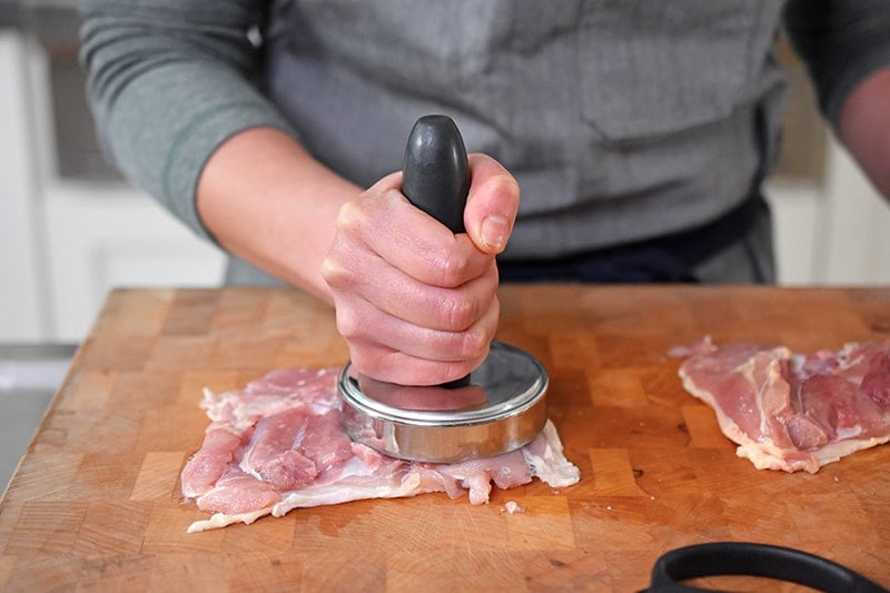 Pounding a bone-less chicken thigh with a meat pounder.