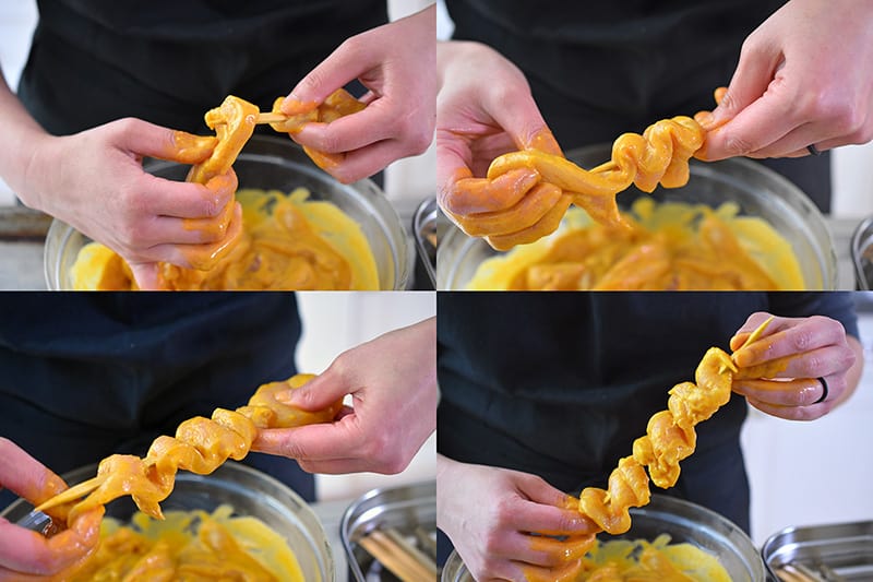 Showing the steps on how to properly skewer the marinated chicken strips onto a wooden skewer. The meat is tightly packed, like an accordion on the skewer.
