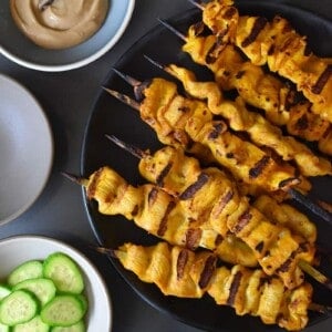 An overhead shot of Chicken Satay and Hoisin No-Nut Sauce along with some sliced cucumbers and cauliflower rice.